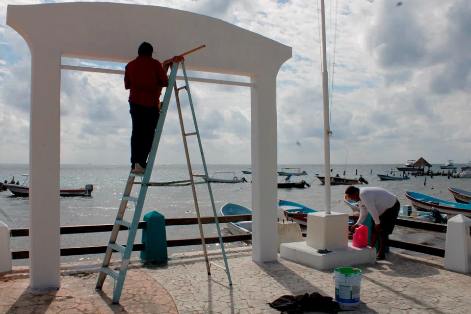 Se realizan labores de pintura en estructuras, como el arco principal en el muelle de pescadores y la rampa para personas con discapacidad.